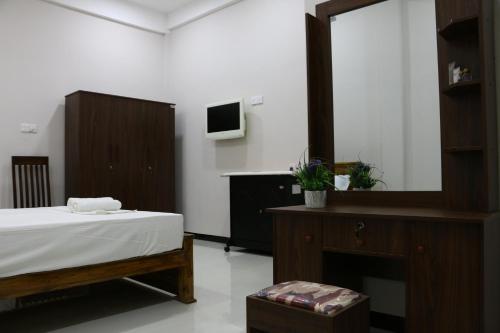 a bedroom with a bed and a dresser and a mirror at Thisha Hotel & Restaurant in Jaffna