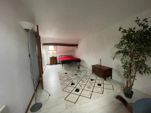 ein Wohnzimmer mit einem roten Bett und einer Pflanze in der Unterkunft Marie Galante in Sully-sur-Loire