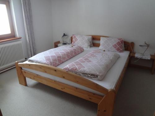 una cama de madera con almohadas rosas y blancas. en Haus Sonnegg, en Fieberbrunn