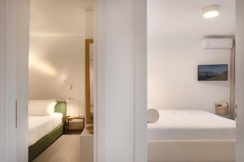 a white bedroom with two beds and a mirror at The Beach House, Skaloma in Nafpaktos