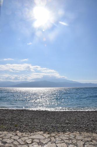 a beach with the sun shining over the ocean at The Beach House, Skaloma in Nafpaktos
