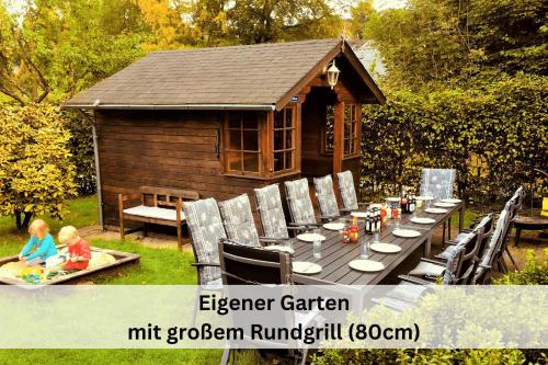 a picnic table and chairs in front of a cabin at Ferienhaus Pape - 300m2, 15 Betten - mit großem privatem Garten, Pool, Dart, Sauna-, Grill- und Spielbereich - Ideal für Familien in Eslohe