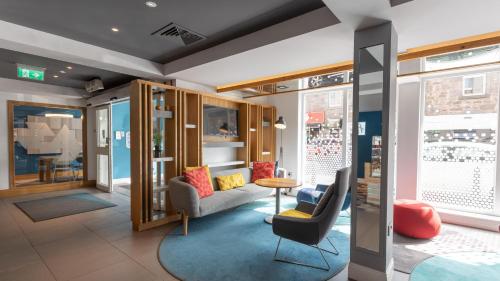 a living room with a couch and chairs and windows at Holiday Inn Express Aberdeen City Centre by IHG in Aberdeen