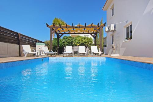 a swimming pool with chairs and a pergola at Nissi Dreams Villa in Ayia Napa