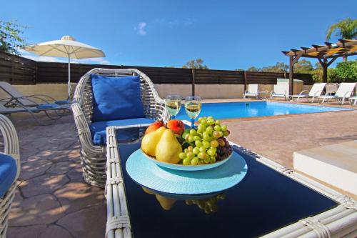 a bowl of fruit on a table next to a pool at Nissi Dreams Villa in Ayia Napa