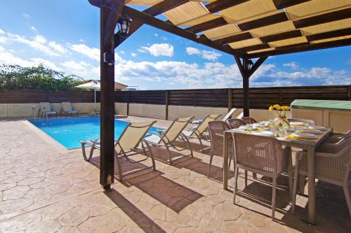 a patio with a table and chairs next to a pool at Nissi Dreams Villa in Ayia Napa
