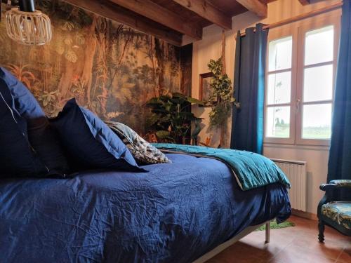 1 dormitorio con cama con sábanas azules y ventana en Maison Cassin47, en Lavergne