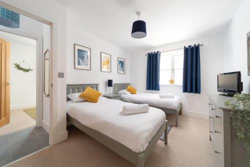 a bedroom with two beds with blue curtains and a tv at Goodleigh Cottage in Goodleigh