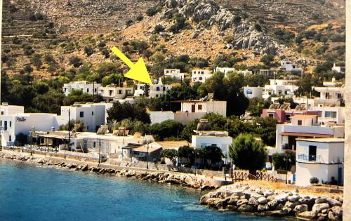 a yellow plane flying over a town next to the water at Elefanti Nani in Livadia
