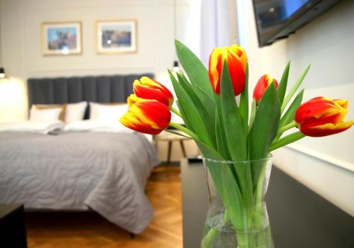 eine Vase mit roten und gelben Tulpen in einem Schlafzimmer in der Unterkunft Falcon Apartment Center 1 Warszawa Centralna in Warschau