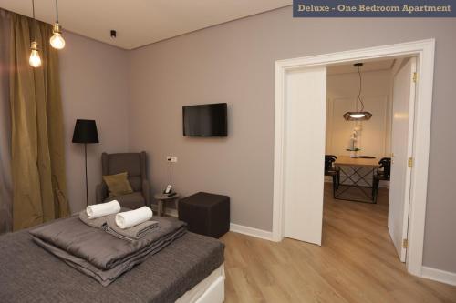 a bedroom with a bed and a chair and a television at Moment Boutique Apartments in Belgrade