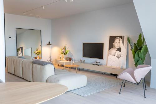 a living room with a couch and a flat screen tv at The Loft - Full Sea View - use of hotels Sauna and Pool in Cadzand