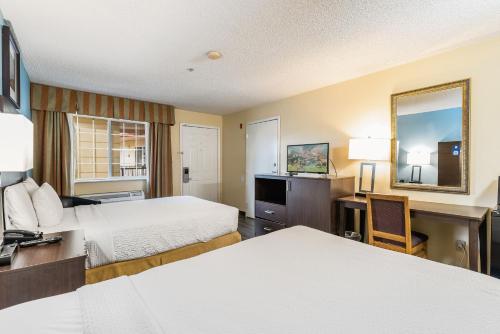 a hotel room with two beds and a desk at Days Inn by Wyndham Federal Way in Federal Way