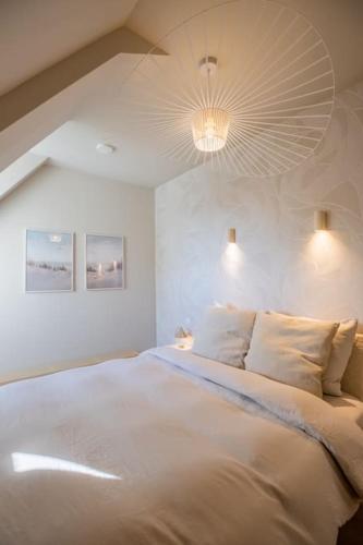 a white bedroom with a large bed with pillows at The Loft - Full Sea View - use of hotels Sauna and Pool in Cadzand