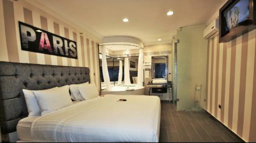 a bedroom with a large white bed and a bathroom at Cedros Inn Boutique Hotel in Guayaquil