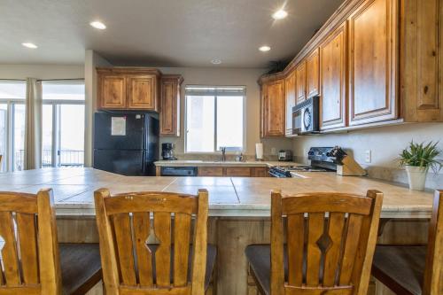 a kitchen with wooden cabinets and a kitchen island with chairs at 2012 LP PS4, Private Balcony with Beautiful Mountain Views, and Great Clubhouse Amenities in St. George