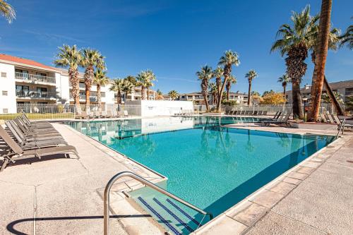a swimming pool with chairs and palm trees at 2012 LP PS4, Private Balcony with Beautiful Mountain Views, and Great Clubhouse Amenities in St. George