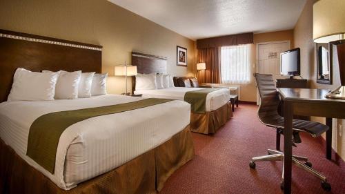 Habitación de hotel con 2 camas y escritorio en SureStay Hotel by Best Western Floresville, en Floresville