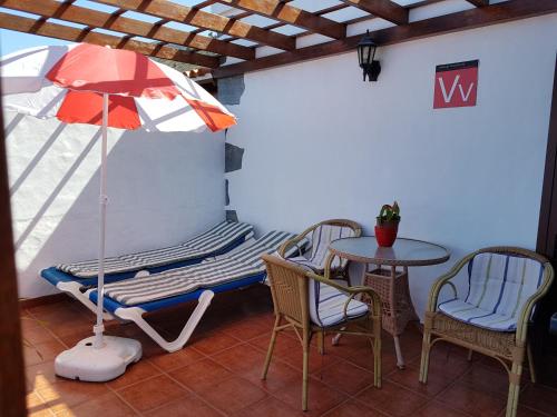 een veranda met een stoel, een parasol en een tafel bij House the Viñas 2 With views of the sea, the mountains and the volcanoes in Fuencaliente de la Palma