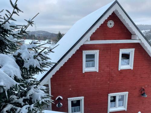 a red house with a clock on the side of it at Wioska w Sowich Sokolec in Sokolec