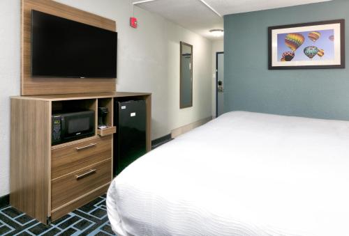 a hotel room with a bed and a flat screen tv at Baymont by Wyndham Chattanooga Eastridge in East Ridge