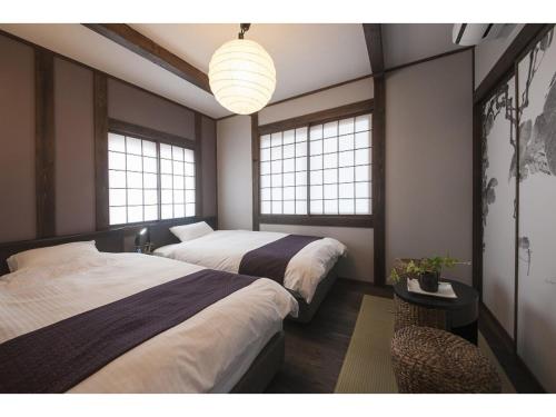 dwa łóżka w pokoju z dwoma oknami w obiekcie Daimaru-un - Vacation STAY 56043v w mieście Kanazawa