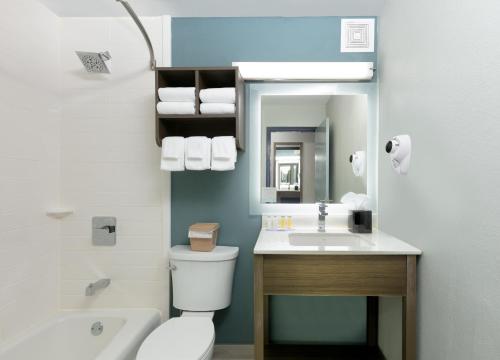 a bathroom with a toilet and a sink and a mirror at Baymont by Wyndham Chattanooga Eastridge in East Ridge