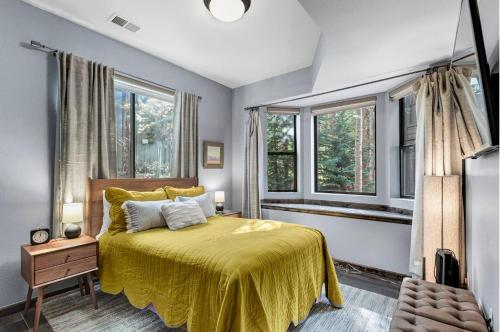 1 dormitorio con 1 cama con colcha amarilla y ventanas en Luxury Modern Townhome steps to ski lifts and downtown with Nature at your patio en Breckenridge