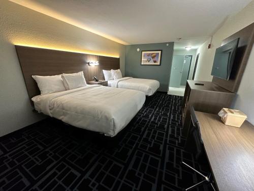 a hotel room with two beds and a television at Baymont by Wyndham Chattanooga Eastridge in East Ridge