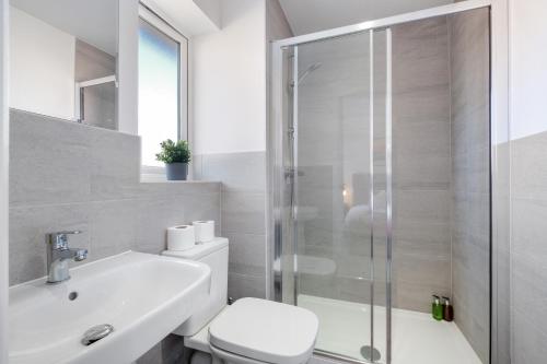 a bathroom with a shower and a toilet and a sink at Modern 5 Bedroom 3 Bathroom Serviced House Aylesbury with Parking By 360Stays in Aylesbury