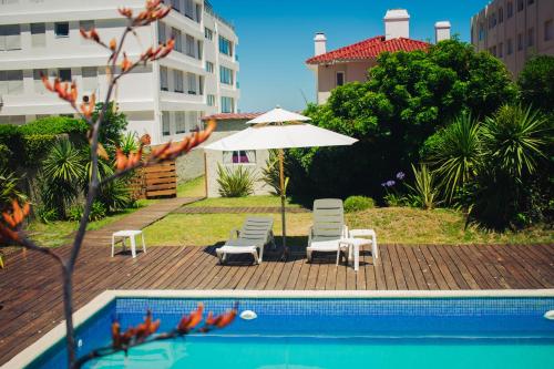 a swimming pool with two chairs and an umbrella at Hotel Milano in Punta del Este