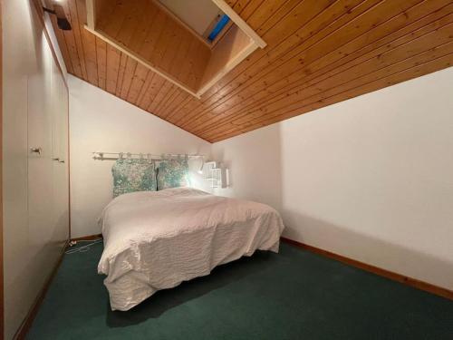 sypialnia z łóżkiem i drewnianym sufitem w obiekcie Appartement duplex avec vue sur le domaine skiable w mieście Le Grand-Bornand