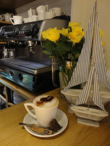 a cup of coffee and a vase with yellow roses at The Manor House in Puncknowle