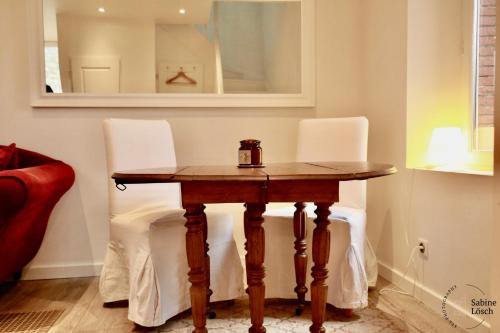 a wooden table with two white chairs around it at Chez Marcel in Le Vaudreuil