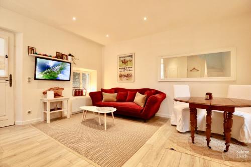 a living room with a red couch and a table at Chez Marcel in Le Vaudreuil