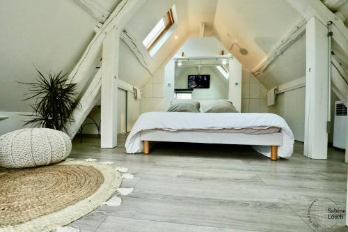 een slaapkamer met een wit bed op zolder bij Chez Marcel in Le Vaudreuil