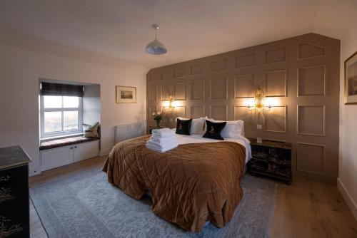 a bedroom with a large bed with a large headboard at Kipney Farmhouse - luxury hunting lodge in Perth