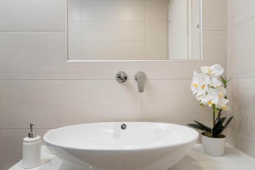 a white sink in a bathroom with a mirror and flowers at Bliss Holidays Spot in Fira