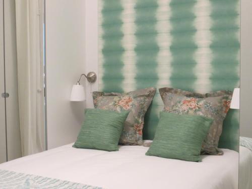 a bed with four pillows and a green headboard at Apartamento Roma in Lisbon