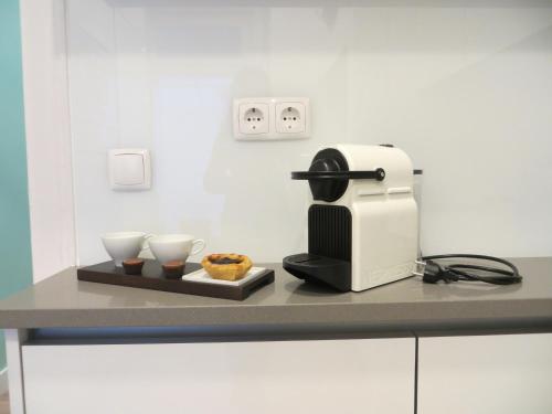 a coffee maker and two cups on a counter at Apartamento Roma in Lisbon