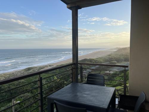 a balcony with a table and chairs and the ocean at Beach Escape on the coast at apartment 78 Sancta Maria in Amanzimtoti