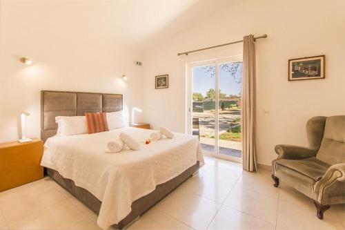 a bedroom with a bed and a chair and a window at Villa Saudade in Lagoa