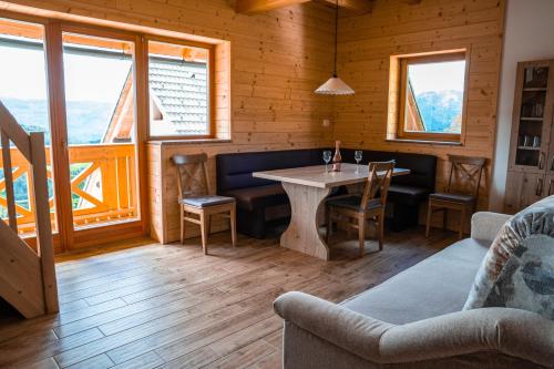 Una sala de estar con mesa y sillas y ventanas. en A house with the view, en Srednja Vas v Bohinju