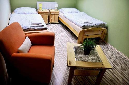 Habitación con 2 camas, silla y mesa. en Penzión Rosenau, en Rožňava