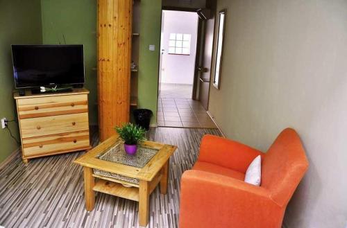 a living room with an orange chair and a table at Penzión Rosenau in Rožňava