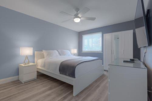 a white bedroom with a bed and a ceiling fan at Once Upon A Tide Oceanview Condo Pet Friendly in Jacksonville Beach