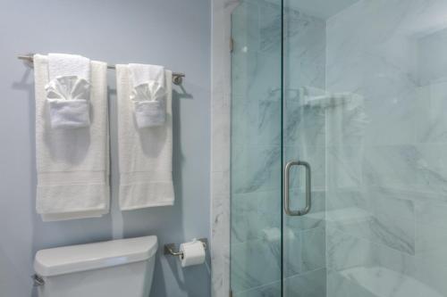a bathroom with a shower and a toilet and towels at Once Upon A Tide Oceanview Condo Pet Friendly in Jacksonville Beach