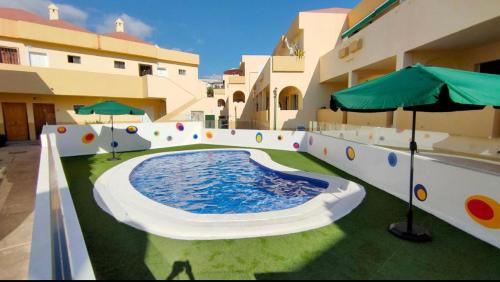 a large swimming pool with an umbrella on a building at Cozy apartment Costa Adeje in Adeje