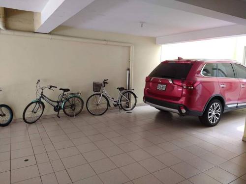un suv rouge garé dans un garage avec deux vélos dans l'établissement Alquiler de apartamento en Lince, à Lima