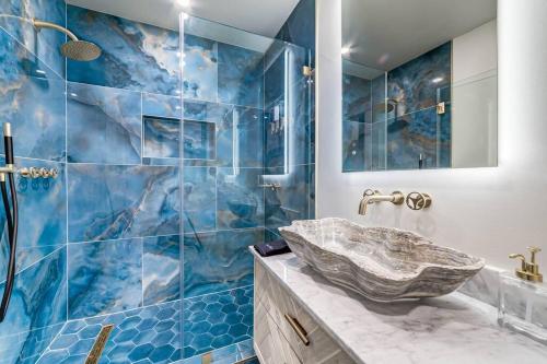 La salle de bains est pourvue de carrelage bleu, d'un lavabo et d'une douche. dans l'établissement Elegant Studio Retreat with Amenities, King St 1 mi, à Alexandria